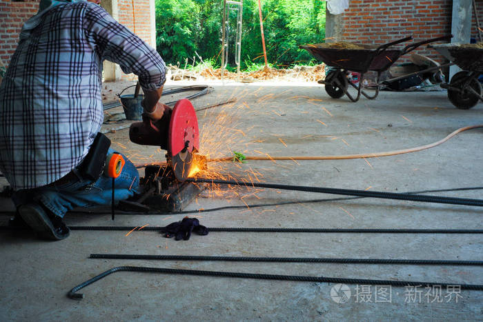 工人在施工现场用电气切割机切割钢筋. 从钢制切割机上射出闪闪发光的
