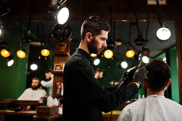 理发店理发师用吹风机工作的英俊胡子男人
