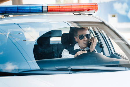 严肃的中年警察戴着墨镜在汽车收音机里说话照片