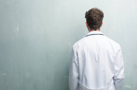 一位年轻友好的医生,他靠在一堵墙上,上面有一个复印的空间,展示着他