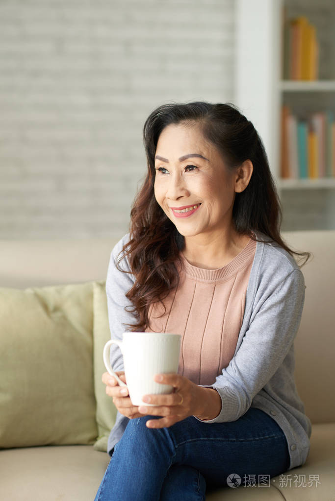 幸福的老妇人坐在家里喝杯咖啡