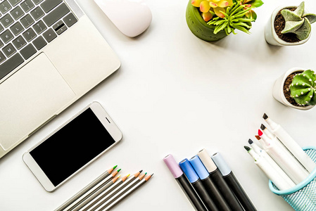 白色桌子上的铅笔,笔记本电脑和盆栽植物,平躺在上面的视图上照片