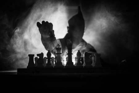 下棋的人. 一个人在棋盘上的可怕的模糊轮廓与象棋人物.