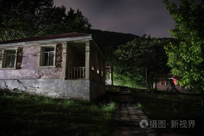 夜晚用月亮或老式乡村住宅在森林中建造的山夜景观,夜晚用云彩和星星.