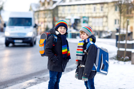 两个小学生在雪中步行上学照片