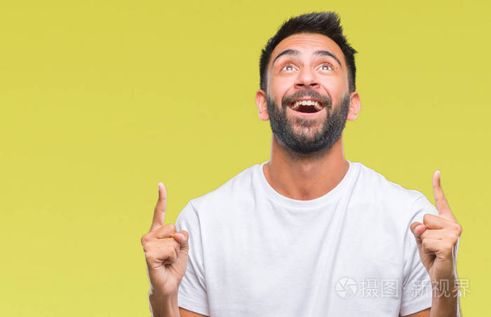 成年西班牙裔男子在孤立的背景上惊讶和惊讶地抬头,手指和举起的手臂.