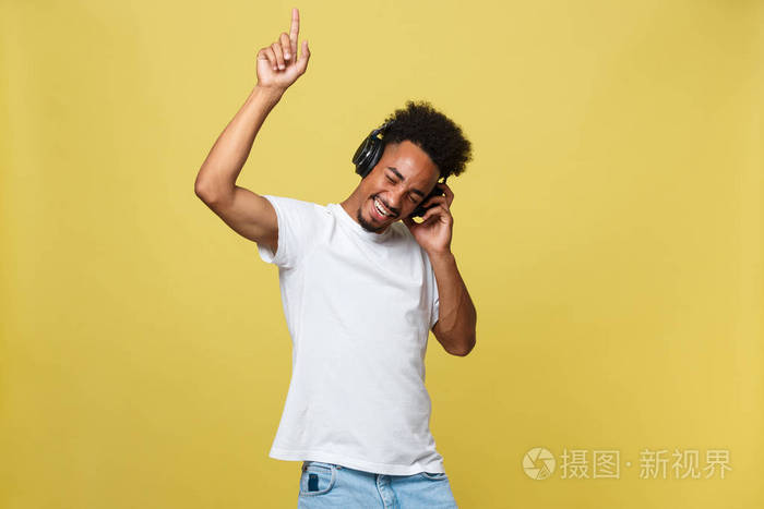 年轻的非洲裔美国人戴着耳机, 享受金色的音乐背景