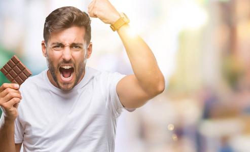 年轻帅哥独自吃巧克力棒恼羞成怒大喊大叫疯狂举手大叫愤怒概念照片