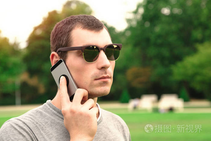 年轻帅哥在公园里用手机