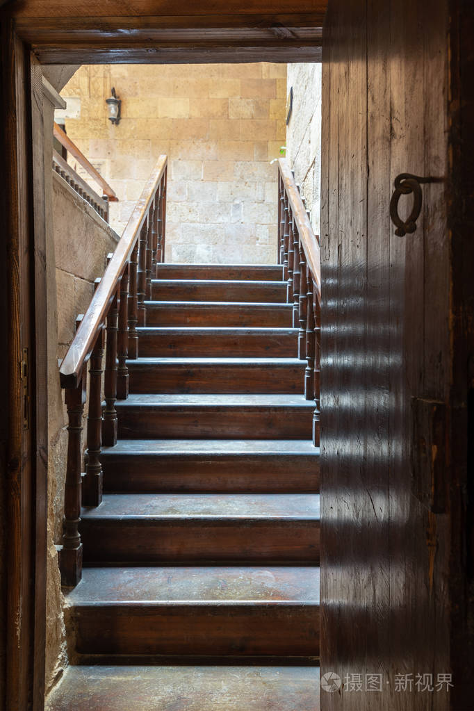 打开的木门露出木制的旧楼梯楼梯的倒影在埃及建筑的房子里埃及开罗