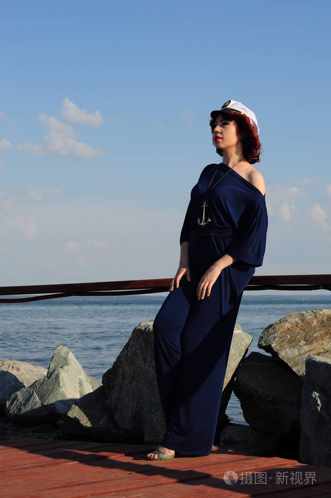 年轻女孩水手在码头上散步在阳光明媚的天气里等着他的船