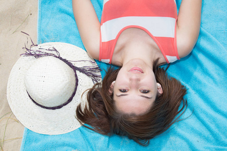 平躺着的年轻女子,在沙滩上躺着蓝色毛巾,暑假期间,在山顶上观看照片