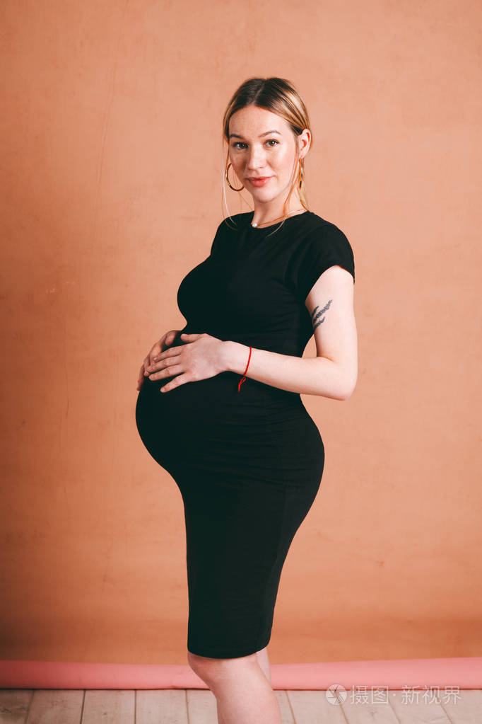 经典肖像可爱美丽的怀孕与漂亮的怀孕金发女子穿着黑色衣服在棕色背景