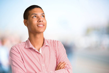 年轻的非裔美国人站着,抬头看着,一边在没有重点的户外背景上微笑照片