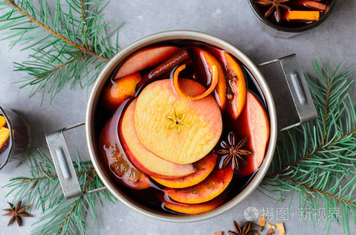 加橙和苹果的热加香料饮料，放在老式的盆栽冬季饮料中