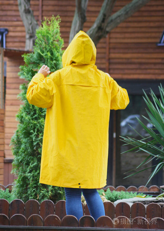 黄色的雨盖从后面秋天穿着黄色雨衣的人
