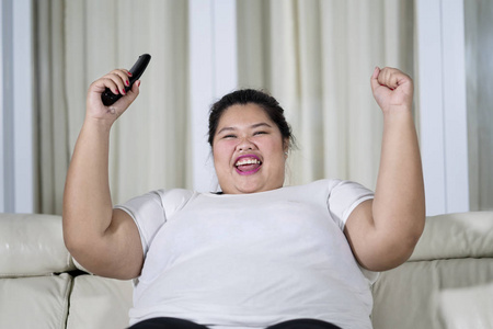 肥胖妇女坐在沙发上高兴地看电视的画面照片