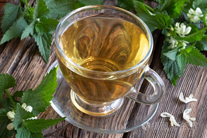 一杯白色的荨麻茶,木桌上放着盛开的苎麻相册