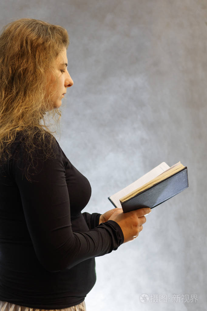 她手里拿着一本书背景很黑