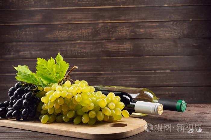 木桌上的酒瓶和葡萄