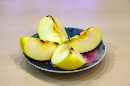 果汁盘子秋天收获后,一个绿色的苹果在彩色盘子上切成四块.