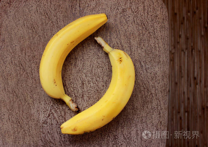 两个成熟的香蕉在棕色纹理的背上
