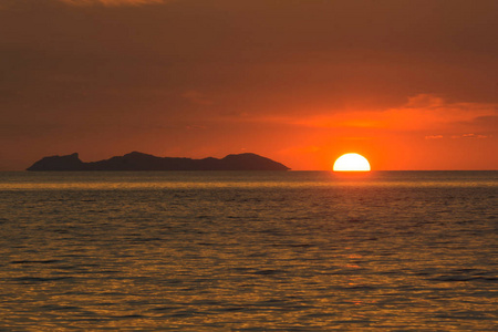 海边的夜晚兜风太阳下山隐藏在大岛附近的地平线上,看着海边的灯光