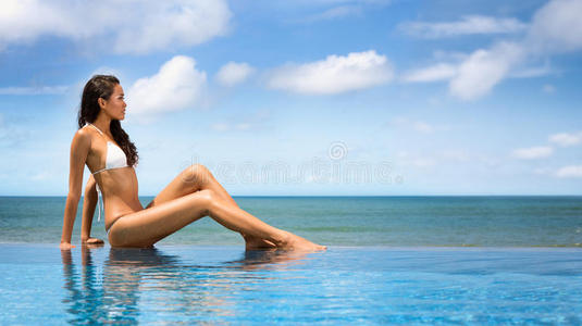 美丽的女人穿着比基尼在海边日光浴