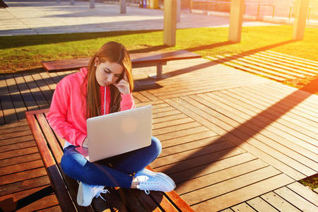 金发女学生集中精力，在校园里忙着使用笔记本电脑