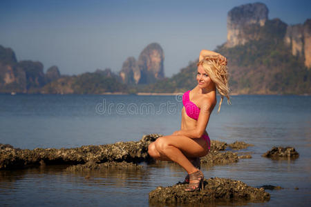 穿着泳衣的金发女孩在石头上抚平头发