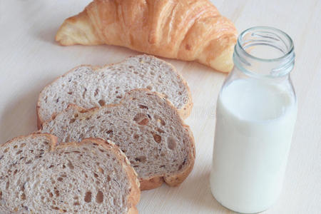 早餐包括全麦面包,牛奶和牛角面包照片