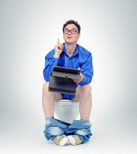 坐在马桶上有平板电脑的商人.照片