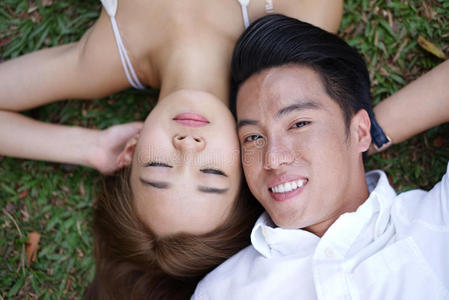 亚洲夫妇躺在草地上