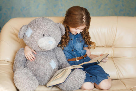 可爱的小女孩和泰迪熊一起读书