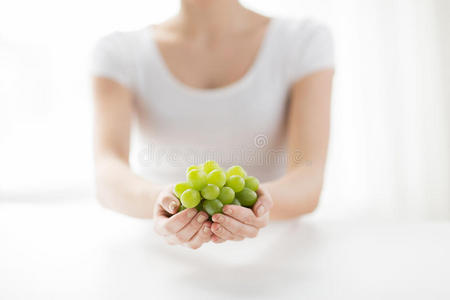 紧握着绿色葡萄束的女人的手