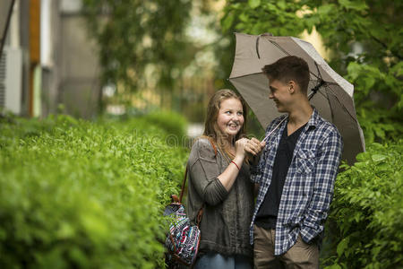 在小雨中，一对男孩和女孩在户外的雨伞下。