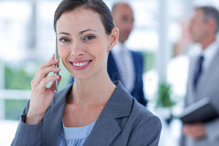 一个女商人和她身后的两个同事用手机