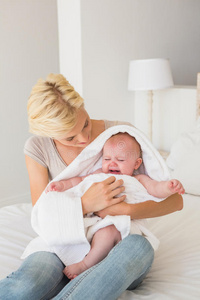 美丽的母亲和她的女婴裹在毛巾里