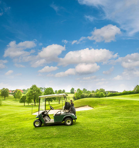 高尔夫球场上的高尔夫球车。 绿色的田野和多云的蓝天