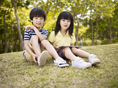 美丽的亚洲孩子坐在草地上