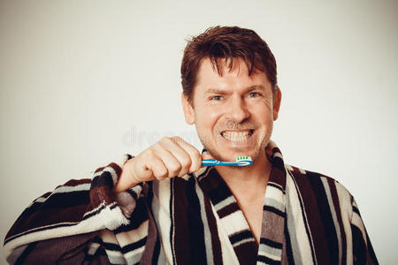 幽默的男人穿着浴袍刷牙，色调