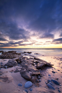 清晨的海洋景观，在岩石海岸和发光的日出