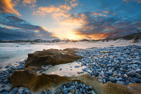 清晨的海洋景观，在岩石海岸和发光的日出