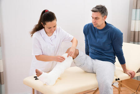 女性医生包扎病人的腿照片