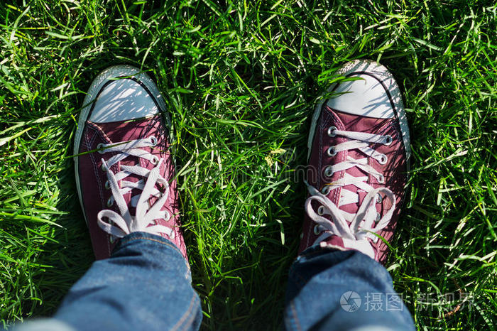 草坪上的蓝色鞋子穿着运动鞋的脚踩在绿草上走在街上脚鞋在大自然中