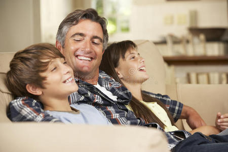 父亲和两个孩子坐在沙发上一起看电视