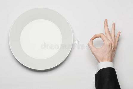商务午餐和健康食品主题男人的手穿着黑色西装，拿着一个白色的空盘子，在上面显示手指的手势