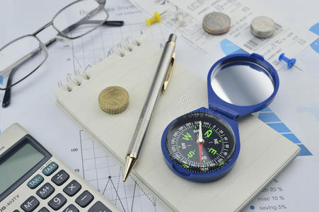 指南针，笔记本上的钢笔和硬币，会计背景