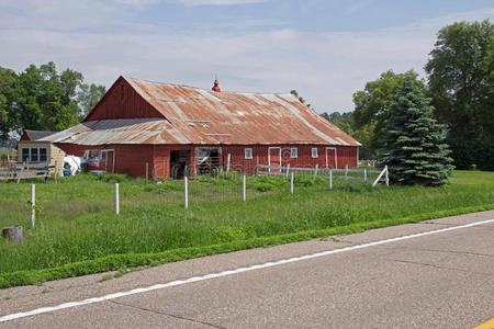 一个旧的红色谷仓，有一个生锈的金属屋顶