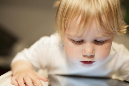 金发婴儿看着屏幕平板电脑